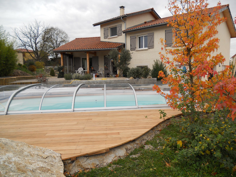 Abri de piscine Modèle Baléares entièrement transparent et téléscopique avec terrasse bois, installé à La Verpillière (Isère)