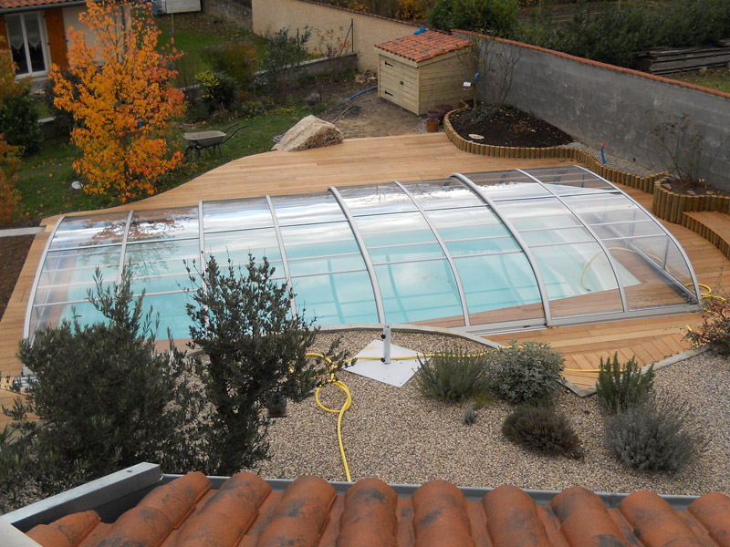 Abri de piscine Modèle Baléares entièrement transparent et téléscopique avec terrasse bois, installé à La Verpillière (Isère)